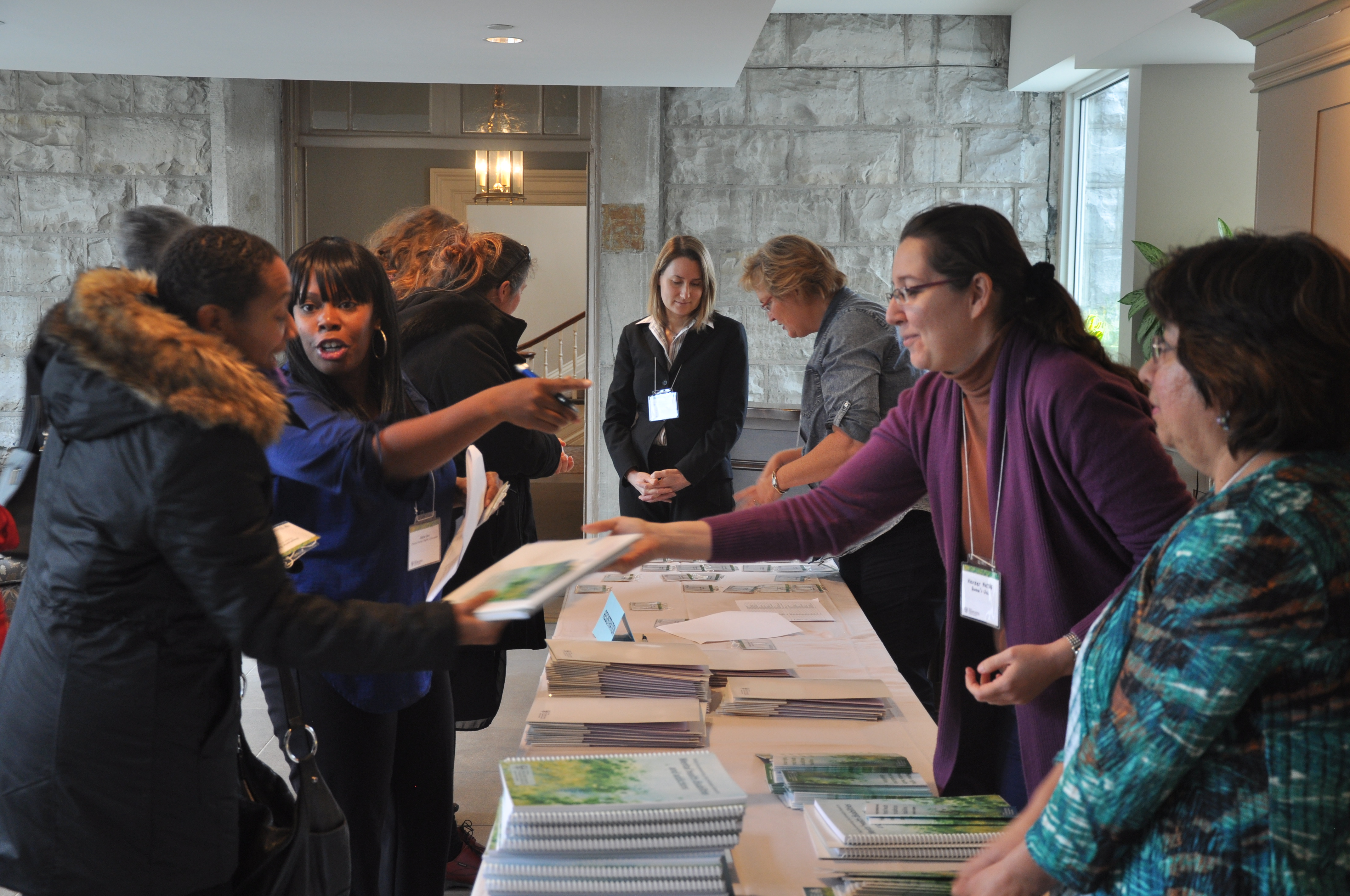 OHRC staff stand at a resource table handing out copies of the mental health policy and speaking with event attendees.