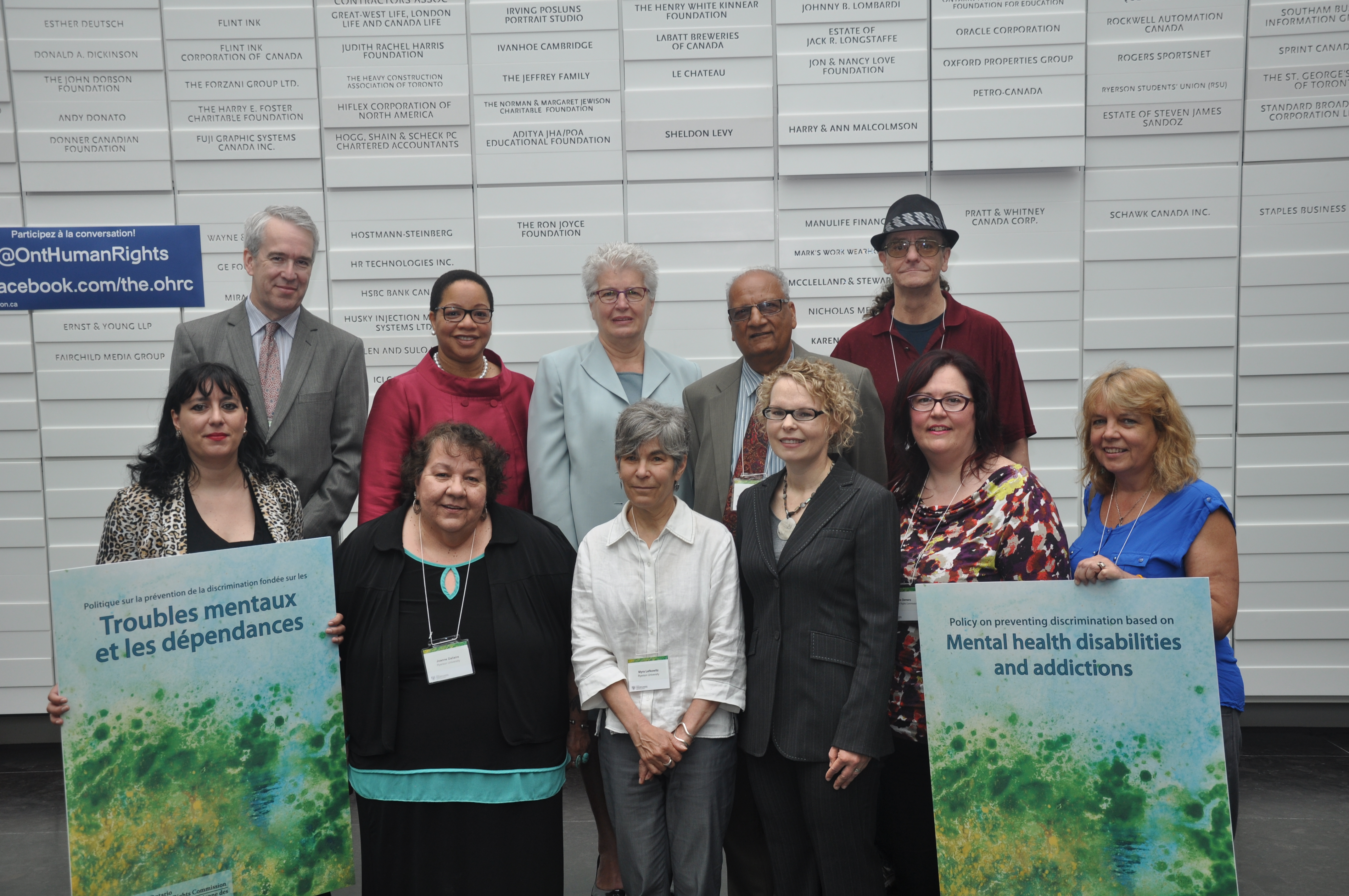 Speakers at the launch of the OHRC’s Policy on preventing discrimination based on mental health disabilities and addictions at Ryerson University stand together, holding posters of the policy cover.