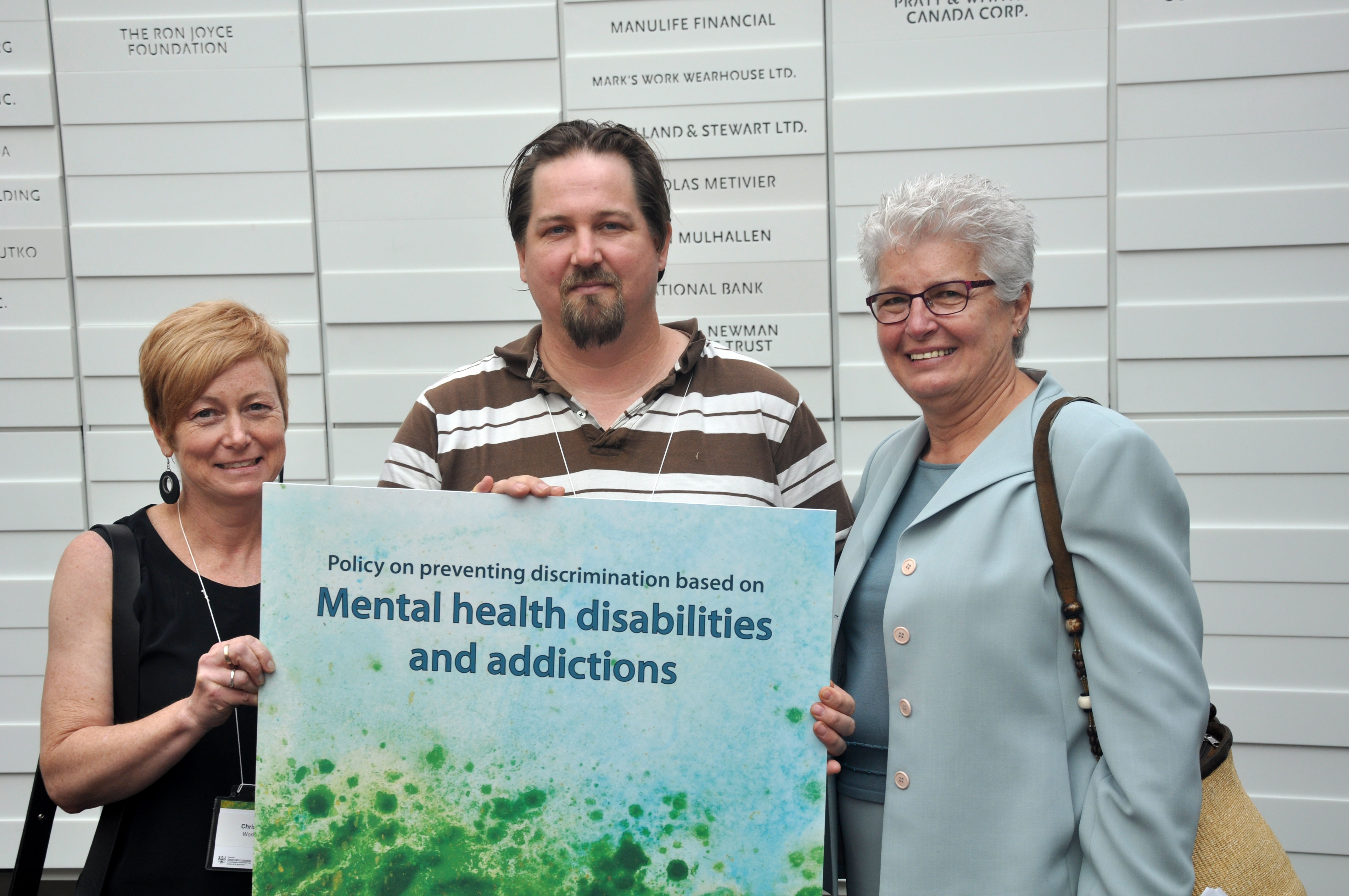 Artist A. Jay, whose artwork was chosen for the policy cover, shows off his work with Chris Mitchell of Workman Arts and Barbara Hall